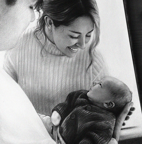 A close-up of a detailed graphite drawing showing a smiling mother in a ribbed turtleneck sweater gently looking down at the baby she is holding in her arms. The baby, wearing a dark knitted onesie, is lying on its back and looking up at its mother. The drawing conveys the love and bond between them.