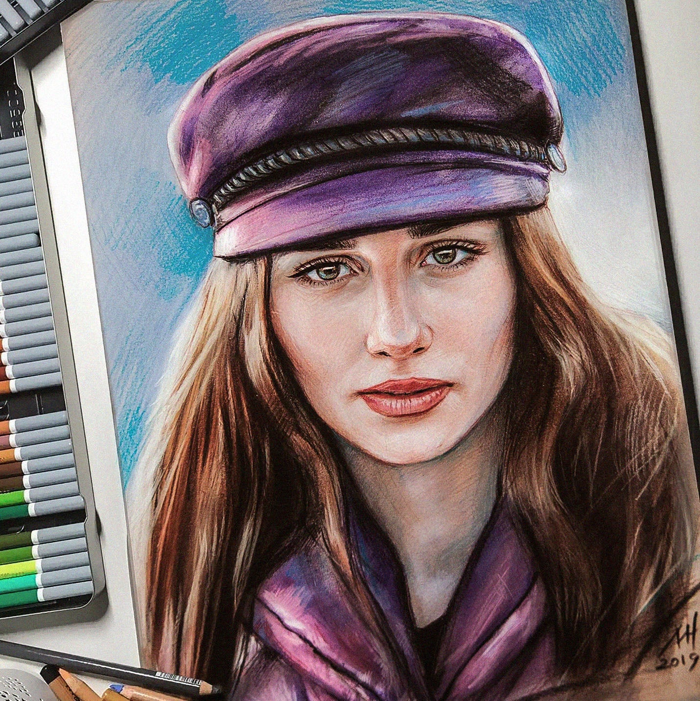 A close-up colored pencil portrait drawing of a woman wearing a purple cap and scarf, shown with drawing tools and markers partially visible at the left edge.